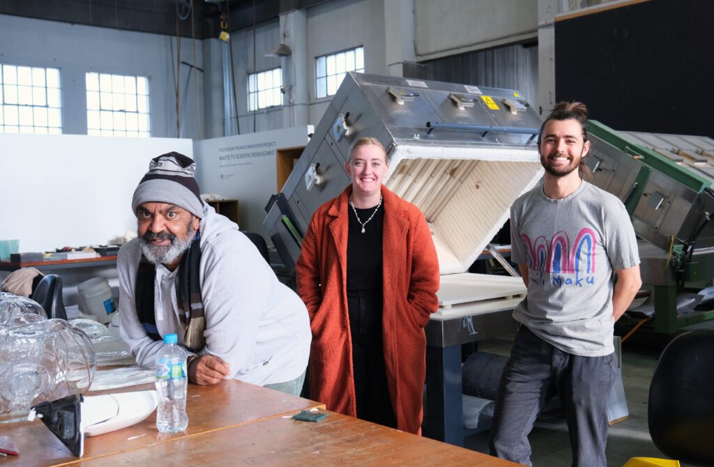 Three artists in standing in the Engine Room at Canberra Glassworks