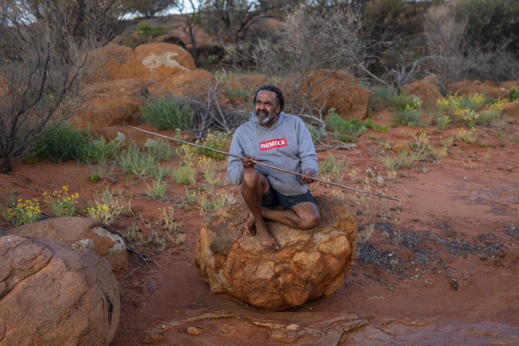 Artist, Robert Fielding, seated on a large rock in Country.